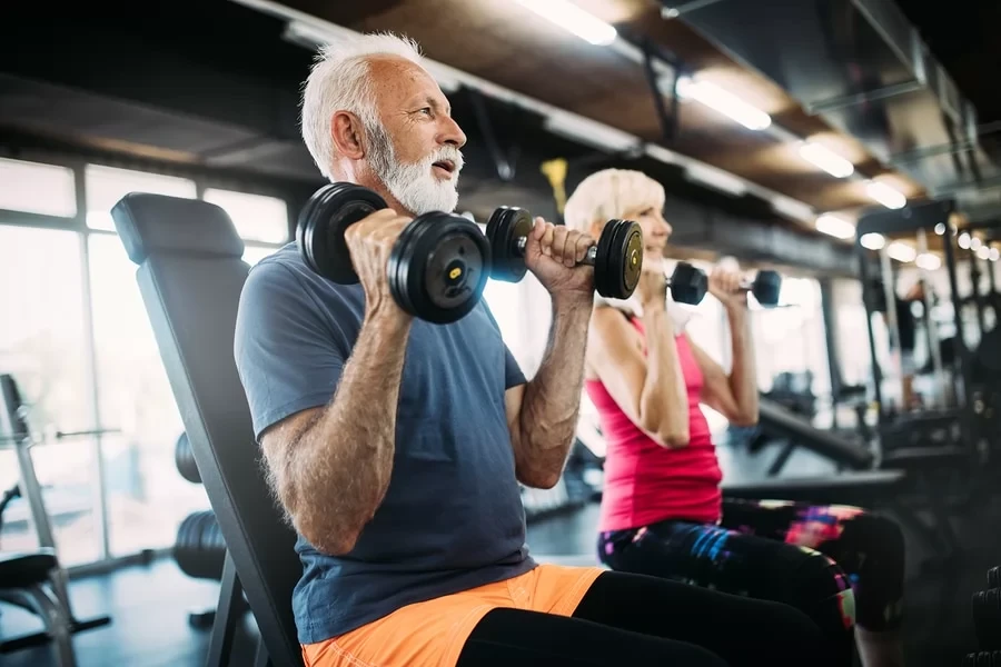 senior man and woman lifting dumbbells for strength training over 70